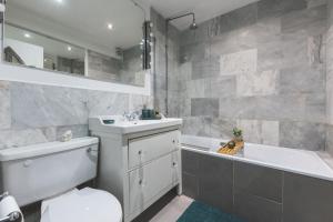 a bathroom with a toilet and a sink and a tub at Sleeps 5, Parking WiFi & Garden, 4 Mins To Station, NEWLY REFURBISHED! in London +23 photos