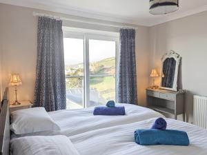 a bedroom with a large bed with blue towels on it at Looe Island View in Torpoint