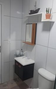 een badkamer met een wastafel, een toilet en een spiegel bij Sonho do Mar in Antonina +92 foto's
