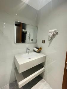 a white bathroom with a sink and a mirror at Tâm Khang Hotel in Móng Cái