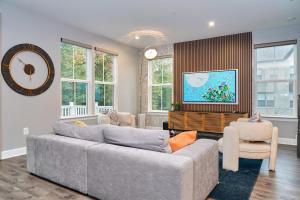 Una sala de estar con un sofá y sillas y un reloj. en Modern Escape Steps from FedEx Field & Near DC, en Largo