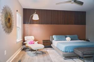 un dormitorio con una cama y una silla en Modern Escape Steps from FedEx Field & Near DC, en Largo