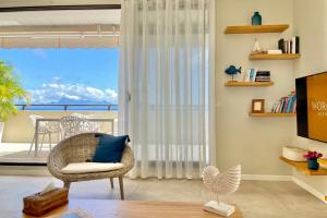 ein Wohnzimmer mit Korbsessel und Balkon in der Unterkunft Luxury Eden & SPA - private jacuzzi - Sunset lagoon view - pool - Wifi in Punaauia