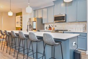Una cocina con gabinetes azules y una gran isla con taburetes de bar. en Modern Escape Steps from FedEx Field & Near DC, en Largo