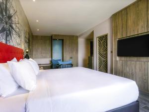 a bedroom with a white bed and a flat screen tv at Mercure Langkawi Pantai Cenang in Pantai Cenang +103 photos