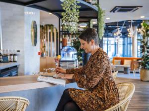 a man sitting in a chair at a counter at Ibis Styles Rouen Centre Rive Gauche in Rouen