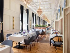 a dining room with white tables and chairs at Raffles Europejski Warsaw in Warsaw