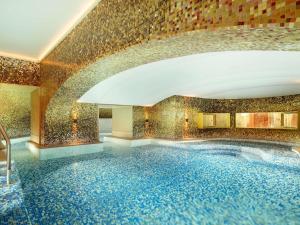 a swimming pool in a building with a tile wall at Raffles Europejski Warsaw in Warsaw