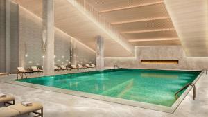 a swimming pool in a hotel with chairs around it at The Reserve Hotel Luoyang, Curio Collection By Hilton in Luoyang