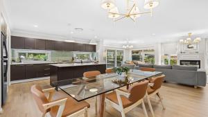 een keuken en woonkamer met een glazen tafel en stoelen bij Holiday Retreat in Pokolbin