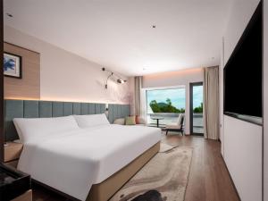 a bedroom with a large white bed and a television at Hilton Garden Inn Zhoushan Mount Putuo in Zhoushan