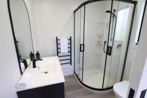 a bathroom with a glass shower and a sink at Modern Tata Beach Escape - Spacious New Retreat in Tata Beach +11 photos