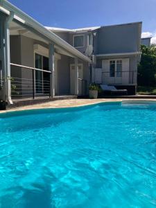 a large blue swimming pool in front of a house at villa Whakata in Saint-Leu