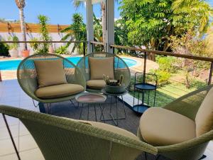 a patio with chairs and a table and a pool at villa Whakata Saint Leu in Saint-Leu