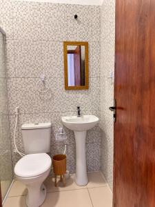 a bathroom with a toilet and a sink and a mirror at Maruá Pousada da Lagoa in Jijoca de Jericoacoara