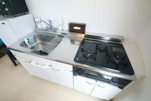 eine Küche mit Herd oberer Ofen neben einer Spüle in der Unterkunft URUMA DOME Neptune9 in Uruma