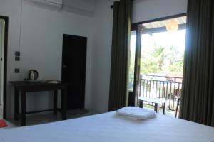 a bedroom with a bed and a table and a balcony at The Leoeye Wilpattu in Pahala Maragahawewa