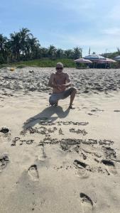a man sitting on the beach with footprints in the sand at Don Bosco Leon in San José de Malpaso