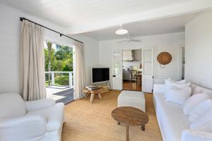 a living room with a white couch and a table at Hinterland Retreat l Fire Pit Scenic Views l Nova Escapes in Goonengerry