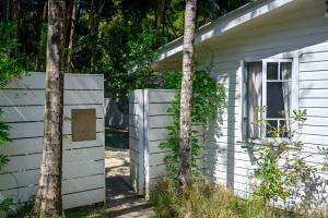 a white house with a window and a tree at Romantic Escape l Firepit & Views l Nova Escapes in Goonengerry