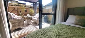 1 dormitorio con 1 cama y balcón con patio en Nature Escape Near Orewa Beach, en Silverdale