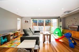 a living room with a couch and a play area at Family-Friendly 2BR Home Near Eastland n BBQ & Toys in Ringwood North