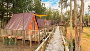 a cabin with a wooden walkway next to a forest at Glamping Eluney Bucalemu in Paredones