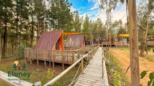 a playground with a wooden walkway and a play structure at Glamping Eluney Bucalemu in Paredones