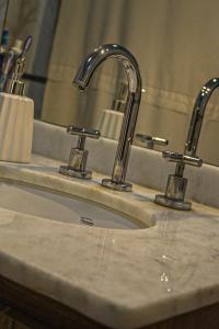 a bathroom sink with two faucets and a mirror at Casa Tafí in Tafí Viejo