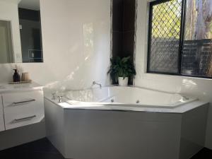 a white bath tub in a bathroom with a window at Rest & Relax at The Secret Garden Getaway in Harrisons Pocket +16 photos