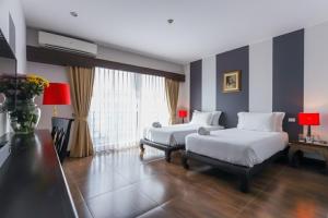 Una habitación de hotel con dos camas y un escritorio. en The Bridge Residence Hotel, en Kanchanaburi 70 fotos más