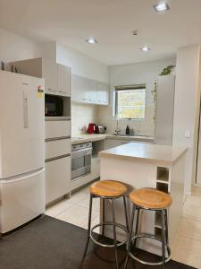 a kitchen with white appliances and two stools at Comfortable in Central Wanaka and Free Parking in Wanaka