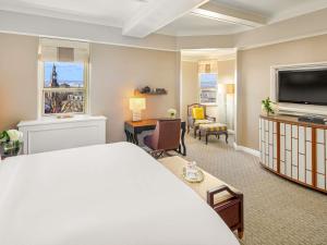 a hotel room with a bed and a television at Fairmont Le Chateau Frontenac in Quebec City