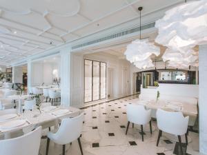 a dining room with white tables and white chairs at Fairmont Grand Hotel Kyiv in Kyiv