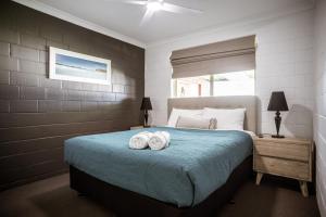 a bedroom with a bed with two towels on it at Archipelago Apartments Esperance in Esperance
