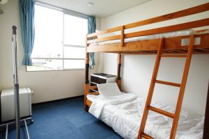 豊山にあるAirport Stay Nagoya Men only guest houseの二段ベッド2組、窓が備わる客室です。