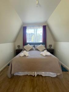 a bedroom with a large bed with two towels on it at CabañasRioBlanco in Chaitén