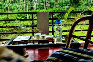 a glass table with a bottle of water and cups at Rainy Cloud Homestay 3B, Balcony, Home Food in Chikmagalūr