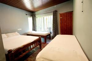 a bedroom with two beds and a window at Rainy Cloud Homestay 3B, Balcony, Home Food in Chikmagalūr