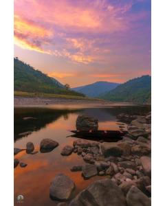 ein Boot auf einem Fluss mit Sonnenuntergang im Hintergrund in der Unterkunft Sunset Riverside Cottage, Umngot River in Dawki