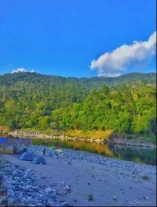 Eine Gruppe von Menschen mit Sonnenschirmen an einem Strand in der Nähe eines Flusses in der Unterkunft Sunset Riverside Cottage, Umngot River in Dawki