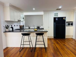 a kitchen with a black refrigerator and two bar stools at Entire House in Berwick close to Parks & Schools in Beaconsfield