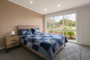 a bedroom with a blue and white bed and a window at Entire House in Berwick close to Parks & Schools in Beaconsfield