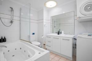 ein weißes Badezimmer mit einer Badewanne, einem WC und einem Waschbecken in der Unterkunft Apartment 9T in Lennox Head
