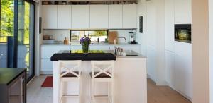 Una cocina con gabinetes blancos y un jarrón de flores sobre una encimera. en Villa With Lake View Over Vättern In Vadstena, en Vadstena