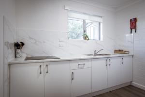 a white kitchen with a sink and a window at Archipelago Apartments Esperance in Esperance +78 photos