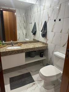ein Badezimmer mit Toilette, Waschbecken und Spiegel in der Unterkunft Flat Comfort Suíte Taguatinga - Sauna, Piscina e Academia - Propriedade Particular 812 in Brasilia + 1 Foto