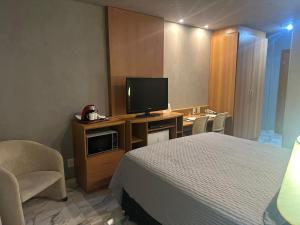 ein Hotelzimmer mit einem Bett und einem Flachbildfernseher in der Unterkunft Flat Comfort Suíte Taguatinga - Sauna, Piscina e Academia - Propriedade Particular 812 in Brasilia