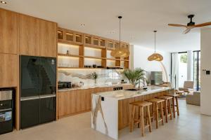 a kitchen with wooden cabinets and a island with bar stools at Elements B3 Villa Bingin in Bingin Beach
