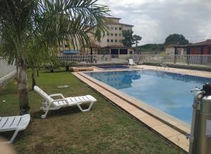a swimming pool with two white chairs and a palm tree at Cittá COP30 in Marituba